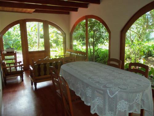 a room with a table and chairs and windows at Refugio de Orquídeas in Oxapampa