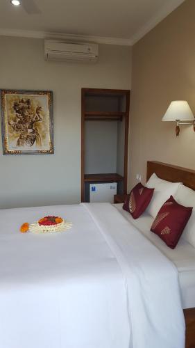 a bedroom with a large white bed with red pillows at Umayuri Inn in Ubud