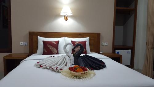 two swans are sitting on a bed with a bowl of flowers at Umayuri Inn in Ubud