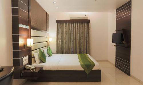 a hotel room with a bed and a television at Hotel Apple Inn Vapi in Vapi