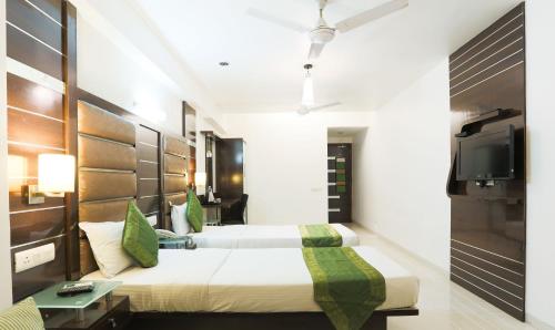 a hotel room with two beds and a tv at Hotel Apple Inn Vapi in Vapi
