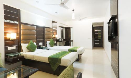 a hotel room with two beds and a tv at Hotel Apple Inn Vapi in Vapi