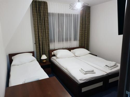 two twin beds in a small room with a table at Noclegi pod Bukowiną in Poronin