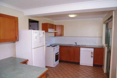 a kitchen with white appliances and wooden cabinets at Beachfront 5, 25 Willow Street in Crescent Head