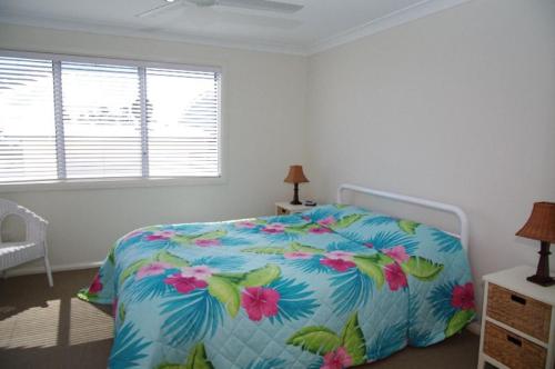 a bedroom with a bed with a floral bedspread at Beach Club 2, 5 Gowing Street in Crescent Head