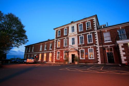 a large brick building with cars parked in front of it at Park Hall Hotel and Spa Wolverhampton in Wolverhampton