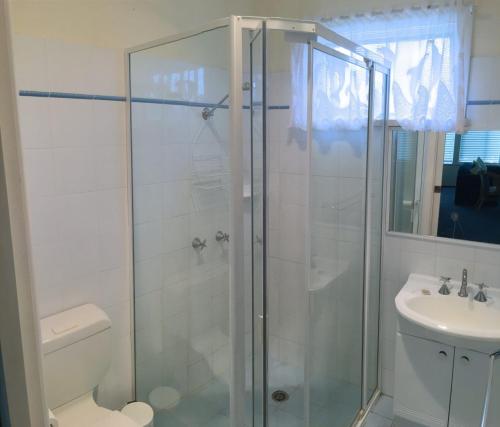 a bathroom with a shower and a toilet and a sink at Lorikeet Retreat, 11 Hodgson Street in Crescent Head