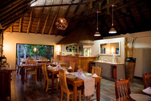 a dining room with tables and chairs and a kitchen at De Old Drift Guest Farm in Addo