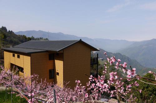 a small house with pink flowers in front of a mountain at The fairy land - Lala Mountain in Fuxing