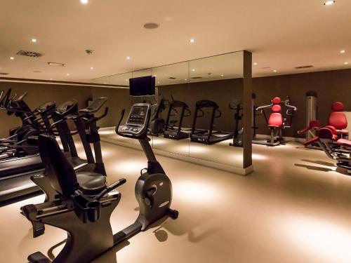 a gym with treadmills and exercise equipment and a mirror at DORMERO Hotel Altes Kaufhaus Lüneburg in Lüneburg