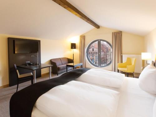 ein Hotelzimmer mit einem großen Bett und einem Fenster in der Unterkunft DORMERO Hotel Altes Kaufhaus in Lüneburg