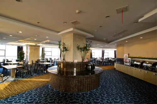 eine Lobby mit einem Restaurant mit Tischen und Stühlen in der Unterkunft GreenTree Eastern Yancheng Binhai Oubaoliya City Square Hotel in Binhai