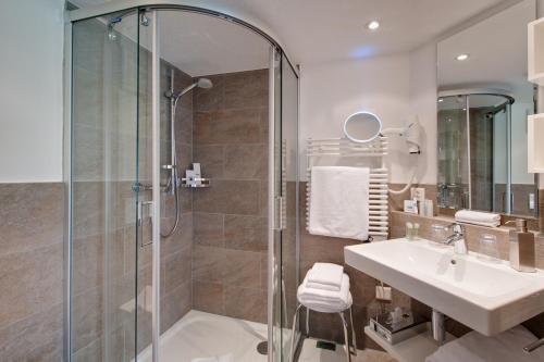 a bathroom with a shower and a sink at Hotel Aristella Swissflair in Zermatt