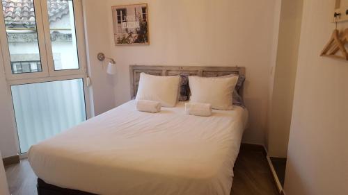 Schlafzimmer mit einem Bett mit weißer Bettwäsche und einem Fenster in der Unterkunft Cativos - Alfama Center District in Lissabon