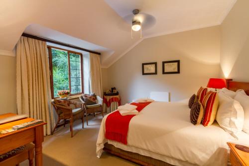 a bedroom with a bed and a desk and a window at Porcupine Ridge Guest House in Sabie