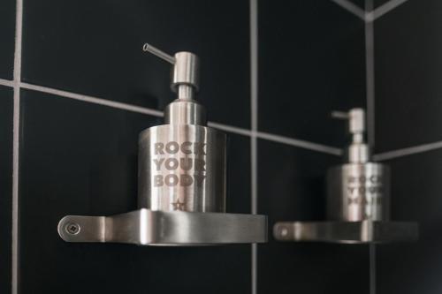 two metal soap dispensers in a bathroom mirror at Design-hotel Rooms and Rumors in Odesa