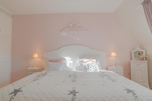 a white bedroom with a large white bed with pillows at Aurora Vendégház in Hévíz