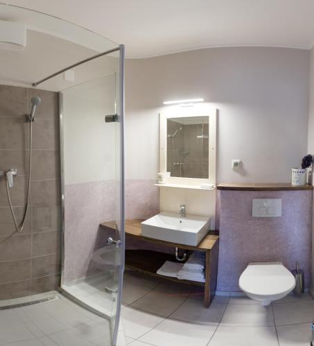 a bathroom with a sink and a toilet and a shower at Aurora Vendégház in Hévíz