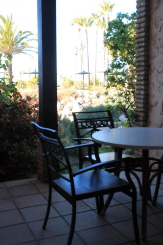 a patio with two tables and chairs and palm trees at Bungalows Bahia Sur in San Fernando