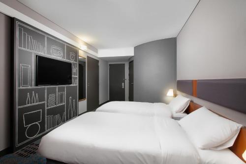 a hotel room with two beds and a flat screen tv at Ibis Ambassador Myeongdong in Seoul