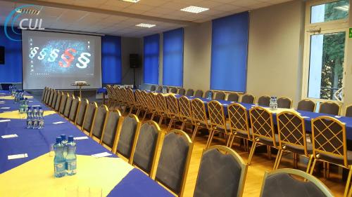 a conference room with tables and chairs and a screen at Ośrodek Wypoczynkowy Olimp in Szklarska Poręba