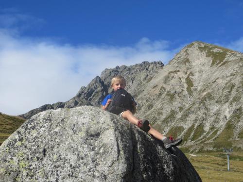 a young boy sitting on a rock in front of a mountain at Garni Reider in Meltina