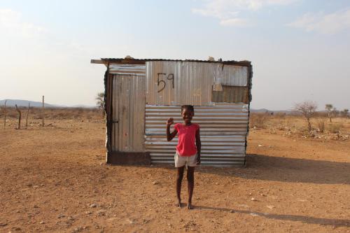 a young boy standing in front of a shack at Etotongwe Lodge in Outjo