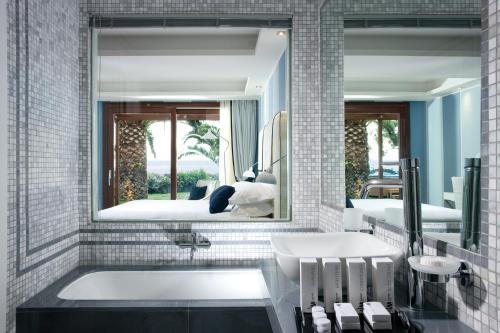 a bathroom with a tub and a mirror at La Plage Resort in Taormina
