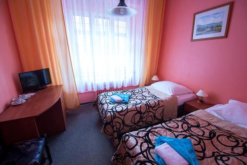 a hotel room with two beds and a desk and a window at Ośrodek Wypoczynkowy Olimp in Szklarska Poręba