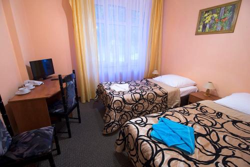 a hotel room with two beds and a desk with a computer at Ośrodek Wypoczynkowy Olimp in Szklarska Poręba