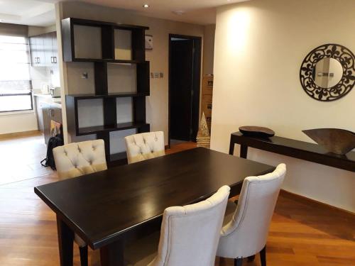 a dining room with a black table and white chairs at Longonot Place Serviced Apartment-Nairobi, City Centre CBD in Nairobi