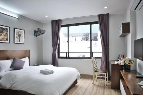 a bedroom with a bed and a desk and a window at V House 6 Serviced Apartment in Hanoi