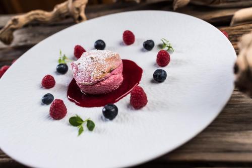 a dessert with powdered sugar and berries on a white plate at Hotel Patriarch in Tirolo