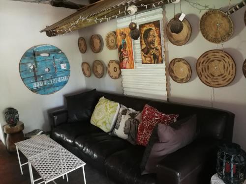 a living room with a black leather couch and many hats at Etotongwe Lodge in Outjo