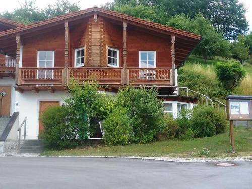 a log house with a balcony on a street at HOME4GOLF Uttlau in Bad Griesbach