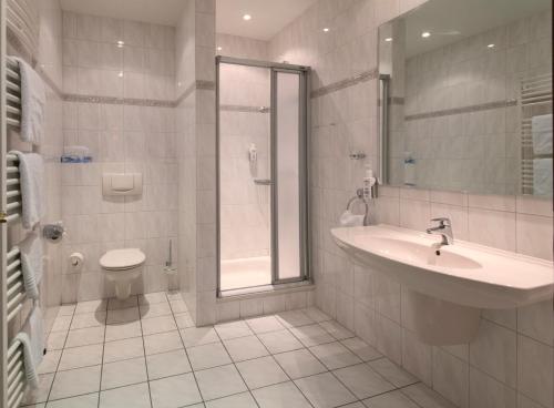 La salle de bains est pourvue d'un lavabo, d'une douche et de toilettes. dans l'établissement Hotel Goos, à Jübek