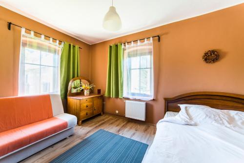 een slaapkamer met een bed, een bank en ramen bij Agroturystyka "Pograniczna" in Ober Wüstegiersdorf