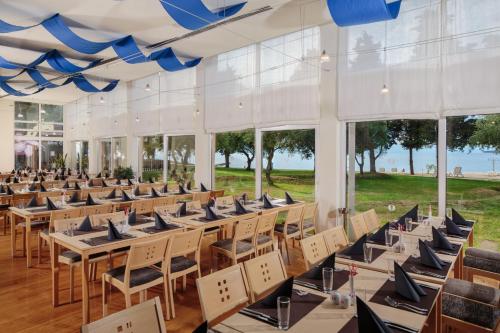 a row of tables and chairs in a room with windows at Garden Suites Umag Plava Laguna in Umag