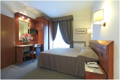 a hotel room with a bed and a desk and a mirror at Hotel Arcadia in Florence