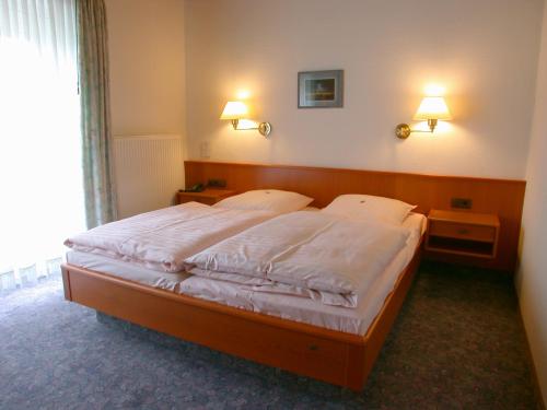 a bedroom with a large bed with white sheets at Hotel Goos in Jübek