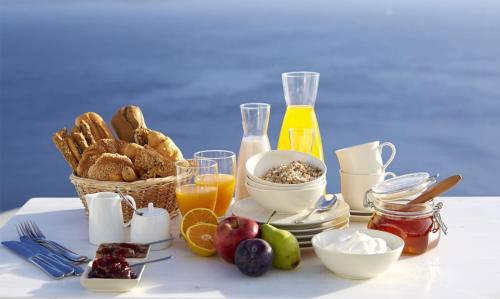 a table with a breakfast of bread and orange juice at Alexander Villas in Imerovigli