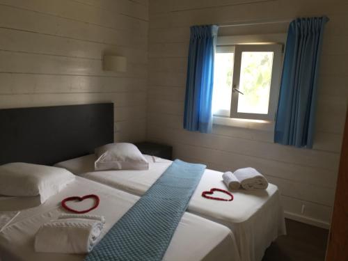 a bedroom with two beds with hearts towels and a window at N`Guembú Nature Resort in Porto Alegre