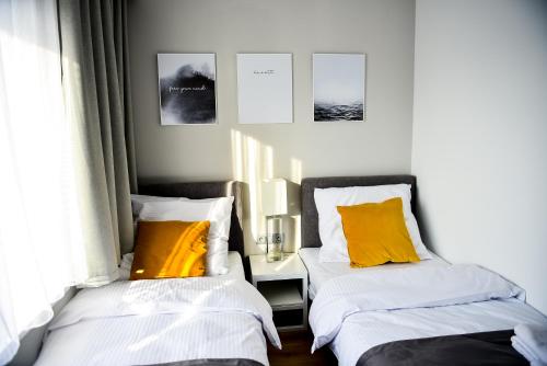 two beds with yellow pillows in a bedroom at Hotel Coliber in Kłobuck
