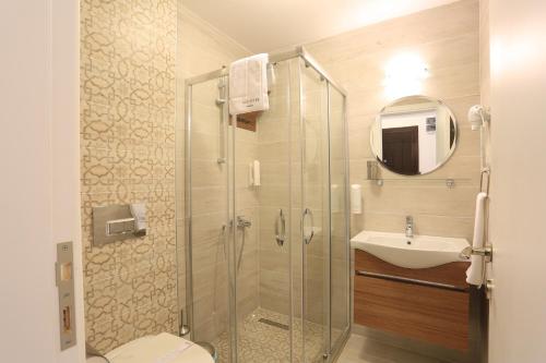 a bathroom with a glass shower and a sink at Alp Suites Lavanta in Akyaka