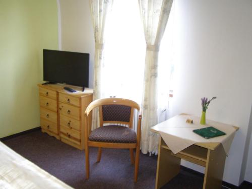 a bedroom with a tv and a chair and a desk at Hotel Garni Belveder in Hřensko