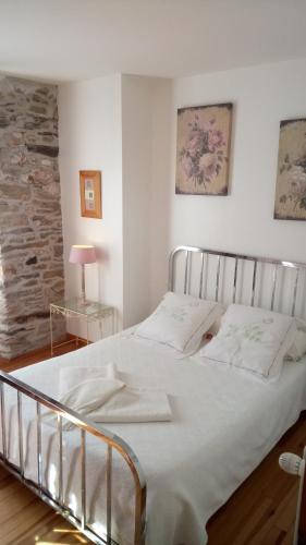 - un lit blanc dans une chambre avec un mur en briques dans l'établissement Château de Colombières sur Orb, à Colombières