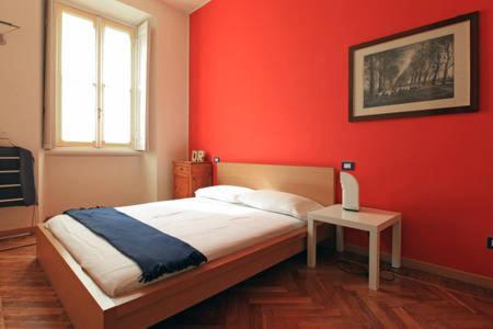 a bedroom with a red wall with a bed and a table at Appartamento centro storico corso magenta cadorna in Milan