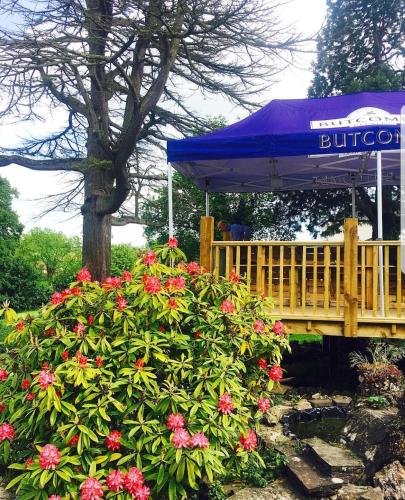 a garden with a bench and a blue umbrella and flowers at Littledean House Hotel in Cinderford