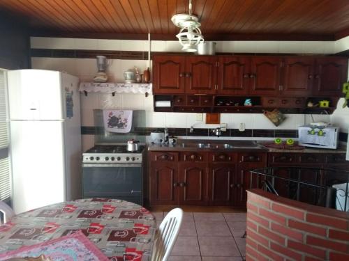 a kitchen with wooden cabinets and a table and a refrigerator at Duplex Tramandaí in Tramandaí