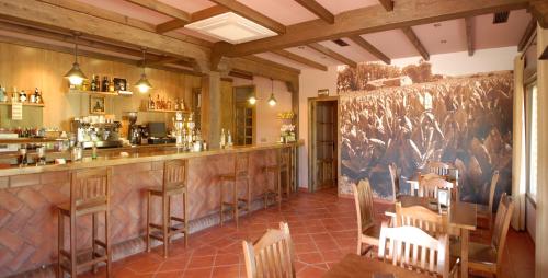 um restaurante com um bar com mesas e cadeiras de madeira em Hotel Rural Robles em Jarandilla de la Vera